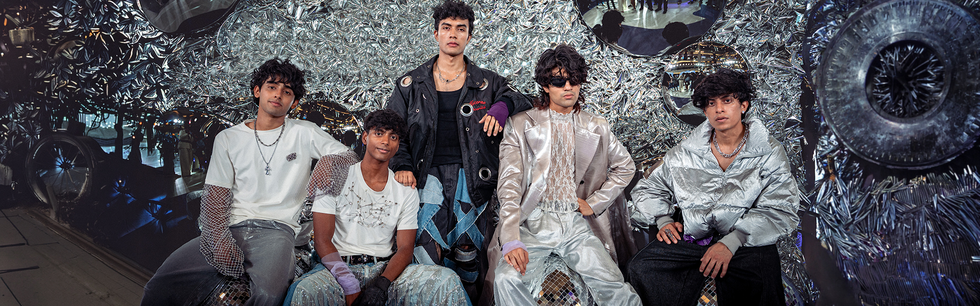 Outstation all five members Bhuvan Shetty Hemang Singh, Mashaal Shaikh, Kurien Sebastian and Shayan Pattem posing together in a silver chrome editorial shoot for the homecoing EP 2026