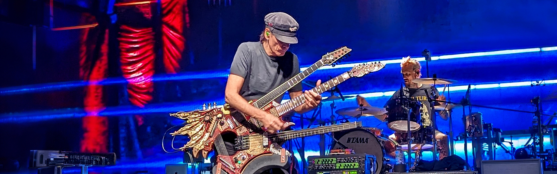 Steve Vaiplaying his ornate multi-necked guitar on stage under blue lighting during the inviolate India tour in December 2023